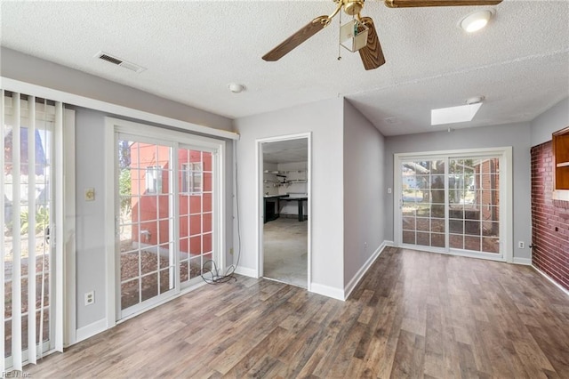 interior space with a skylight, ceiling fan, a healthy amount of sunlight, and hardwood / wood-style flooring