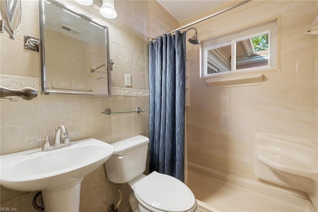 bathroom with sink, a shower with curtain, toilet, and tile walls