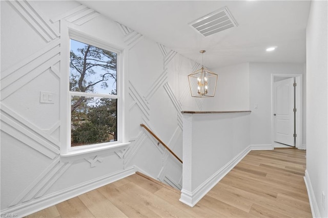 stairway with hardwood / wood-style floors and a notable chandelier