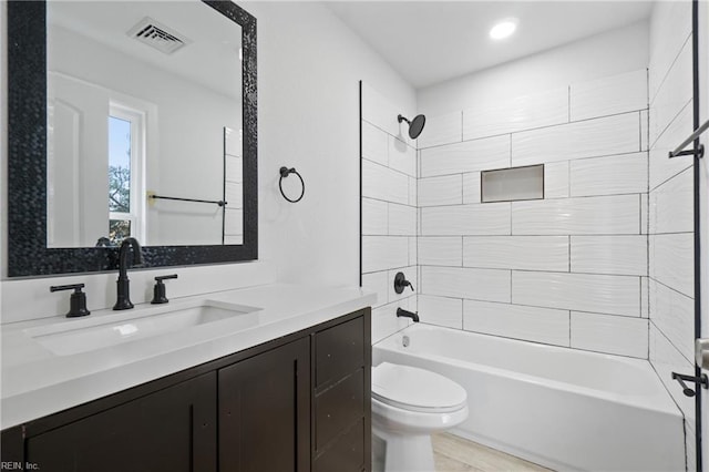 full bathroom with vanity, wood-type flooring, tiled shower / bath combo, and toilet