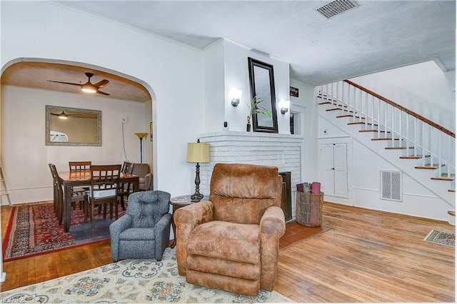 living area featuring a brick fireplace, ceiling fan, and hardwood / wood-style flooring