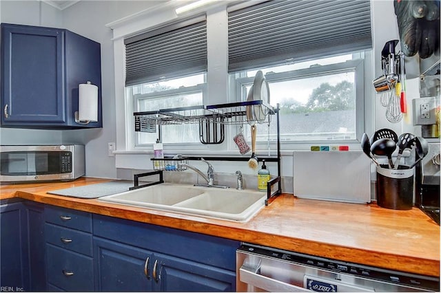 kitchen with blue cabinets, sink, appliances with stainless steel finishes, and wooden counters