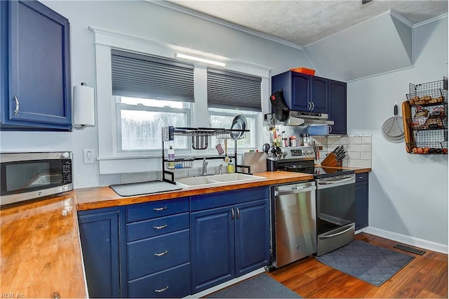 kitchen featuring blue cabinetry, butcher block counters, dark wood-type flooring, and appliances with stainless steel finishes