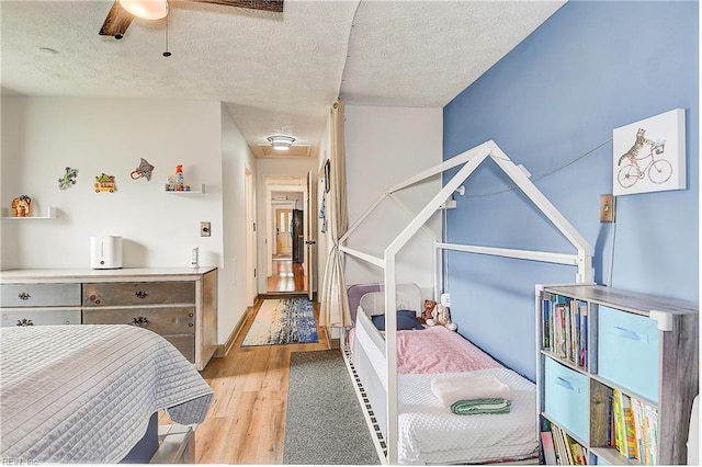 bedroom featuring ceiling fan, light wood-type flooring, and a textured ceiling