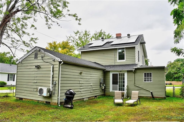 rear view of house with a lawn, ac unit, and solar panels