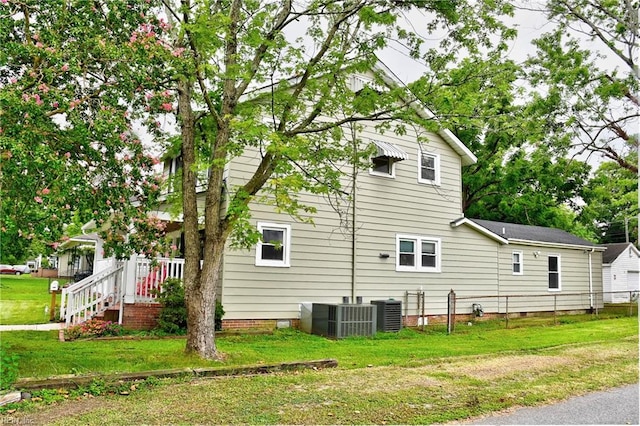 view of side of property with central air condition unit and a lawn