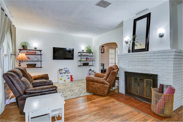 living room featuring a wealth of natural light, wood-type flooring, and a brick fireplace