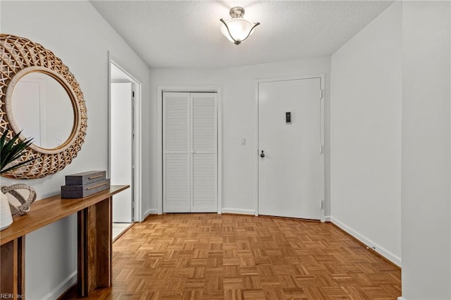 foyer entrance with light parquet floors and a textured ceiling