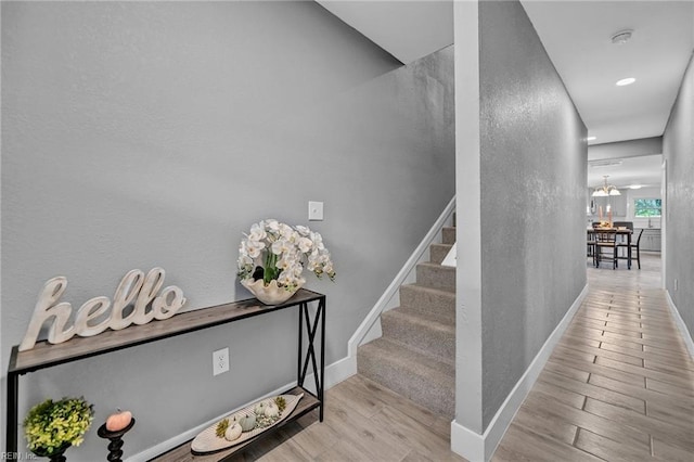 stairway with hardwood / wood-style floors and a chandelier