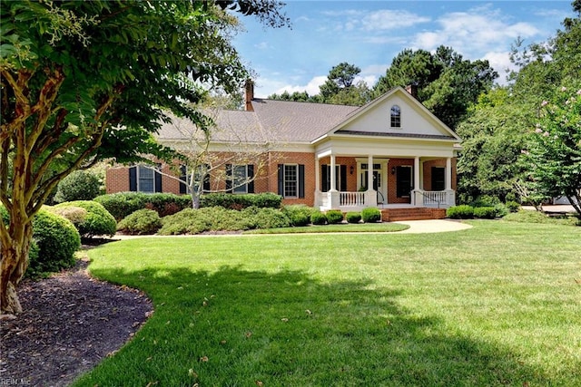 greek revival inspired property featuring covered porch and a front yard