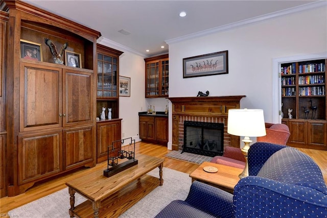 living room with light wood-type flooring, ornamental molding, and a brick fireplace