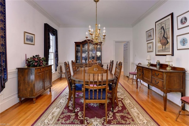 dining area with light hardwood / wood-style flooring, a chandelier, and ornamental molding