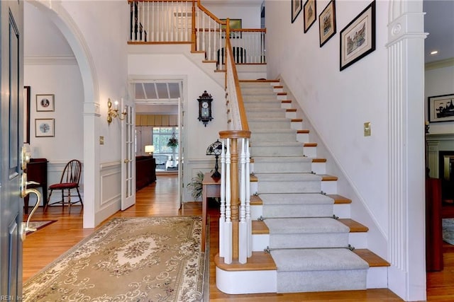 foyer featuring hardwood / wood-style flooring, ornate columns, and crown molding