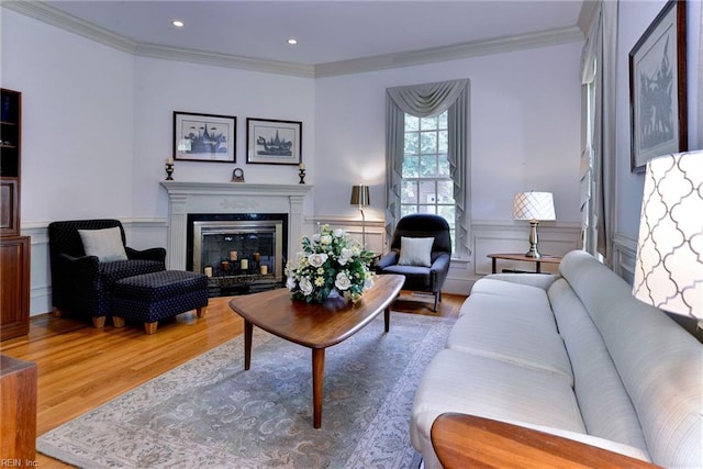 living room with wood-type flooring, ornamental molding, and a high end fireplace