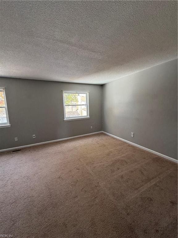 carpeted empty room with a textured ceiling