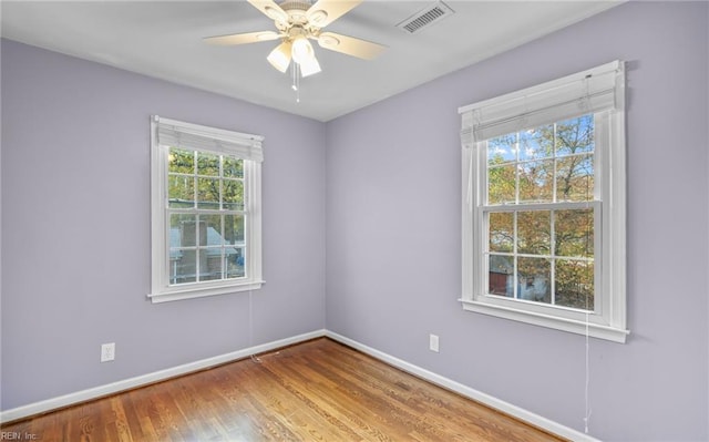 spare room with a wealth of natural light, ceiling fan, and hardwood / wood-style flooring