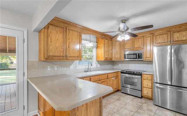 kitchen featuring sink, decorative backsplash, ceiling fan, kitchen peninsula, and stainless steel appliances