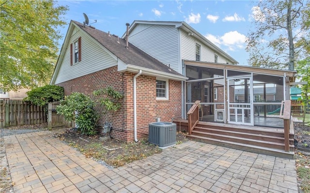 rear view of property with a sunroom, a patio area, and central AC