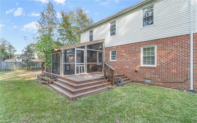 rear view of house featuring a wooden deck, a sunroom, and a yard