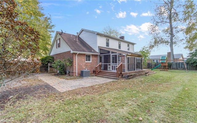 rear view of property with central AC unit, a sunroom, a patio, a playground, and a lawn