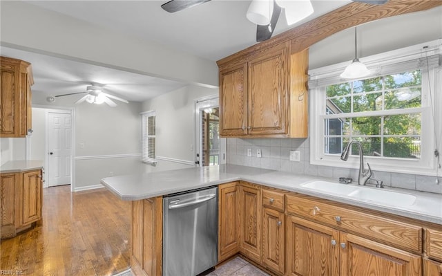 kitchen featuring kitchen peninsula, light wood-type flooring, backsplash, dishwasher, and hanging light fixtures