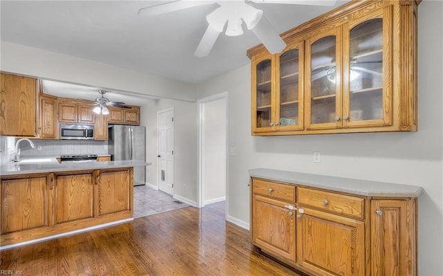 kitchen with decorative backsplash, light hardwood / wood-style floors, sink, and appliances with stainless steel finishes