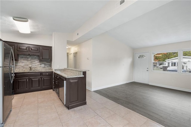 kitchen featuring vaulted ceiling, light wood-type flooring, appliances with stainless steel finishes, dark brown cabinets, and kitchen peninsula