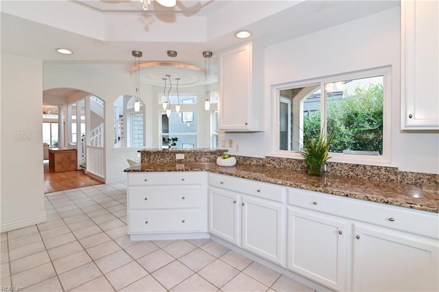 kitchen with white cabinetry, hanging light fixtures, light tile patterned flooring, and dark stone counters