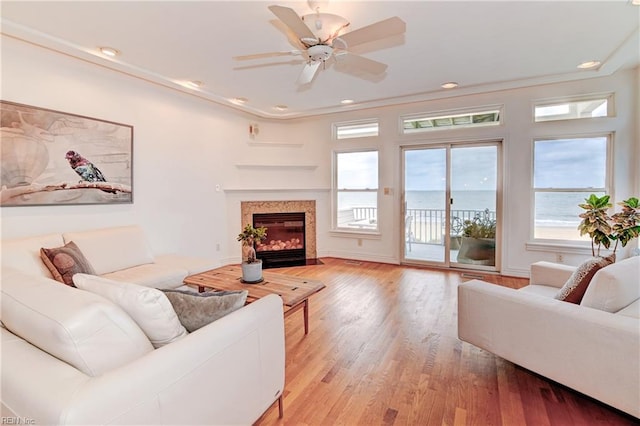 living room featuring ceiling fan, crown molding, a water view, and wood-type flooring