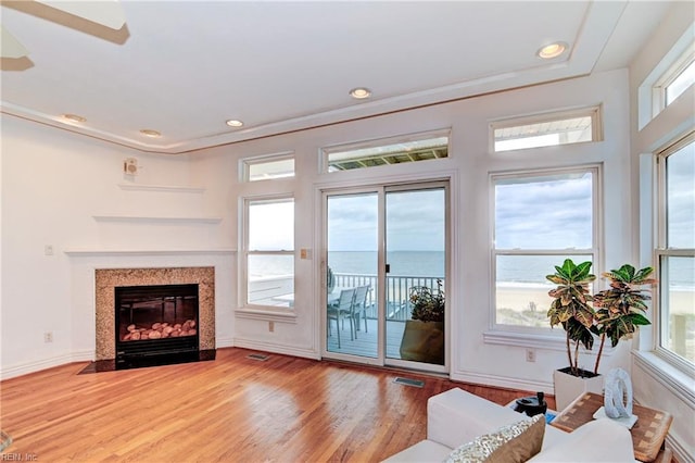 living room with ceiling fan, a healthy amount of sunlight, a water view, and light hardwood / wood-style flooring