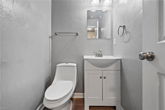 bathroom with hardwood / wood-style flooring, vanity, and toilet