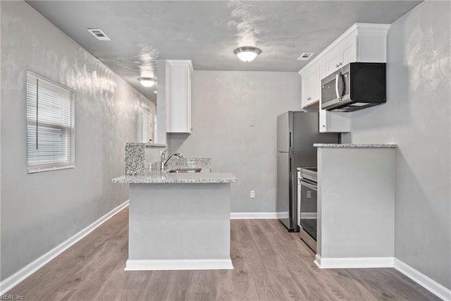 kitchen with white cabinetry, sink, light hardwood / wood-style floors, and appliances with stainless steel finishes