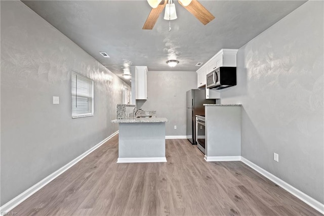 kitchen featuring appliances with stainless steel finishes, light wood-type flooring, ceiling fan, sink, and white cabinetry