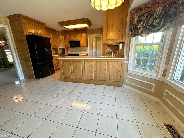 kitchen featuring black appliances, sink, tasteful backsplash, light tile patterned flooring, and kitchen peninsula