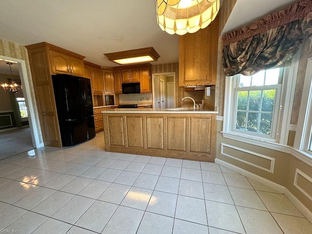 kitchen with an inviting chandelier, black appliances, sink, light tile patterned floors, and kitchen peninsula