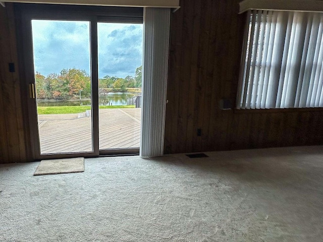 interior space featuring carpet floors, wood walls, and a water view