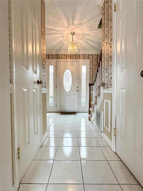 tiled entrance foyer with a textured ceiling and an inviting chandelier