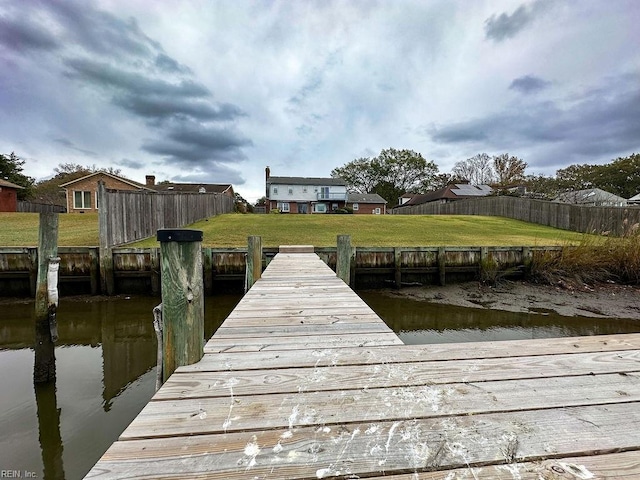 view of dock featuring a lawn and a water view