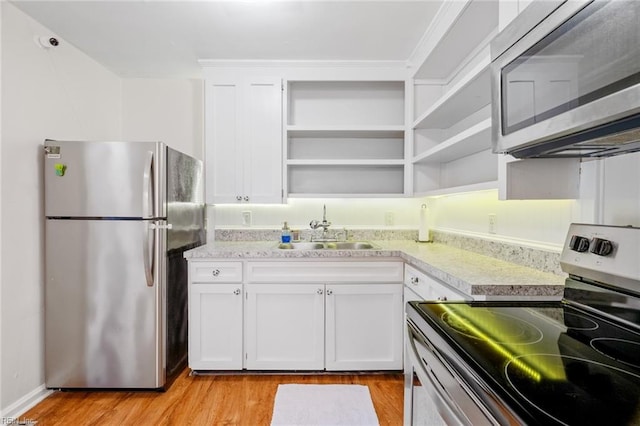 kitchen with stainless steel appliances, white cabinetry, light hardwood / wood-style floors, and sink