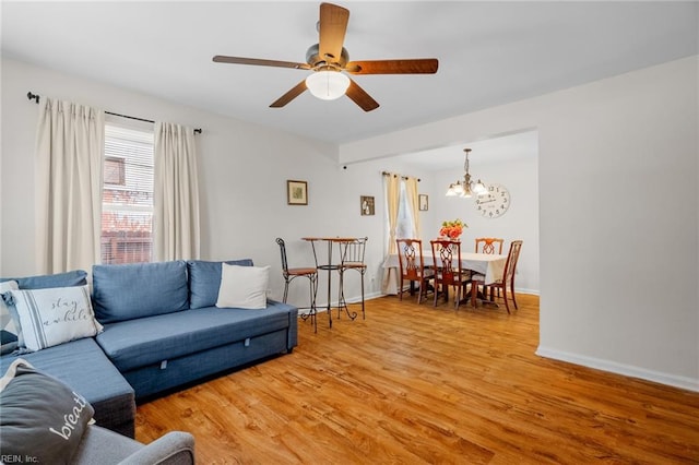 living room with hardwood / wood-style floors and ceiling fan with notable chandelier