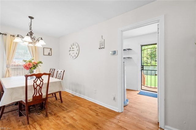 dining space featuring a notable chandelier, wood-type flooring, and a wealth of natural light