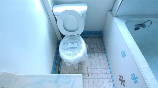 bathroom with tile patterned floors, a bath, and toilet