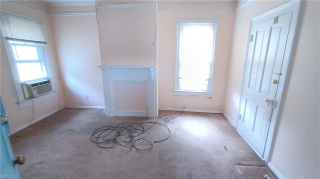 unfurnished living room featuring cooling unit, light colored carpet, ornamental molding, and a wealth of natural light