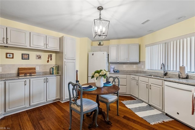 kitchen featuring dark hardwood / wood-style flooring, white appliances, pendant lighting, and sink