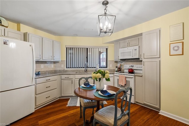 kitchen with decorative backsplash, dark hardwood / wood-style flooring, white appliances, sink, and hanging light fixtures