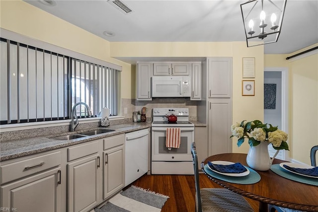 kitchen with white appliances, dark wood-type flooring, an inviting chandelier, sink, and tasteful backsplash