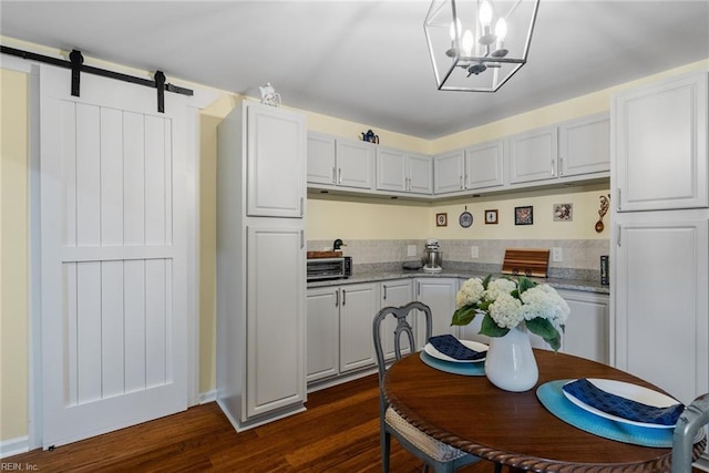 kitchen with a barn door, light stone counters, dark hardwood / wood-style flooring, and white cabinets