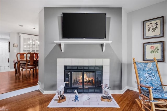 interior details featuring a notable chandelier, wood-type flooring, and a fireplace