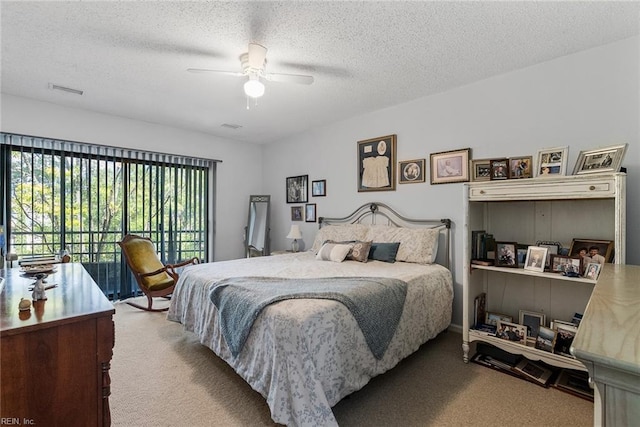 bedroom featuring ceiling fan, access to exterior, carpet floors, and a textured ceiling