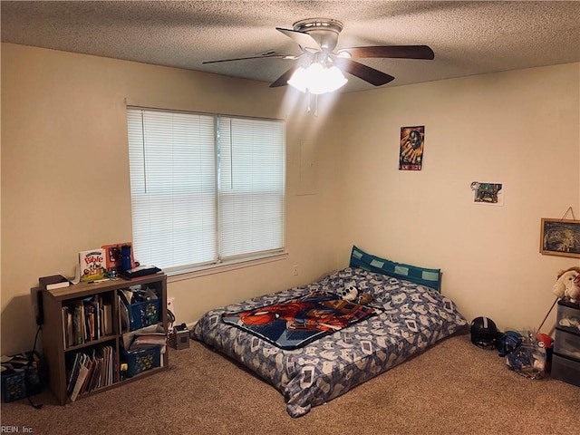 carpeted bedroom with ceiling fan and a textured ceiling